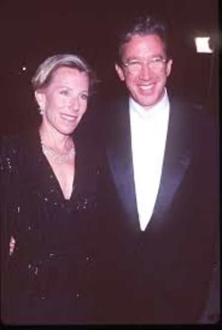 Laura Deibel in a black dress with Tim Allen at a party.